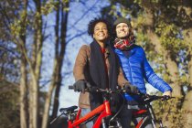 Smiling couple with bicycles in sunny autumn park — Stock Photo