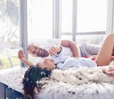 Feathers around playful couple pillow fighting in bedroom — Stock Photo