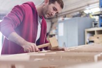 Male carpenter using wood mallet on boat in workshop — Stock Photo