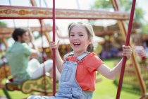 Menina alegre rindo no carrossel no parque de diversões — Fotografia de Stock