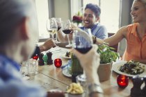 Amici sorridenti che festeggiano, brindando bicchieri di vino al tavolo del ristorante — Foto stock