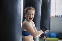 Retrato exuberante boxer feminino gritando, envolvendo pulsos no ginásio — Fotografia de Stock
