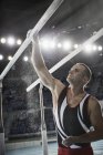 Male gymnast applying chalk powder to parallel bars in arena — Stock Photo