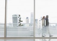 Homme d'affaires et femme d'affaires marchant sur un balcon urbain avec vue sur la ville — Photo de stock