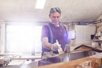 Homem carpinteiro manchando caiaque de madeira na oficina — Fotografia de Stock