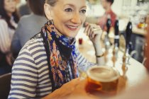 Старшая женщина пьет пиво в баре — стоковое фото