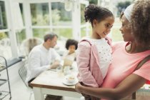 Affectionate mother holding daughter at home — Stock Photo