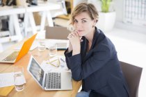 Портрет женщины, сидящей за столом с ноутбуком в офисе — стоковое фото