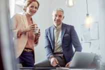 Ritratto sorridente, uomini d'affari fiduciosi bere caffè e lavorare al computer portatile in ufficio — Foto stock