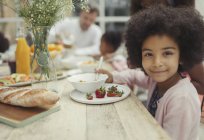 Portrait smiling girl eating strawberries at breakfast table — Stock Photo
