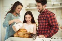 Familie bereitet Weihnachtsessen Truthahn in Küche zu — Stockfoto