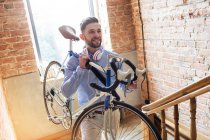 Mann trägt Fahrrad die Ziegeltreppe hinauf — Stockfoto