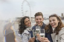 Retrato entusiasta, amigos sonrientes celebrando, brindando champán cerca de Millennium Wheel, Londres, Reino Unido - foto de stock
