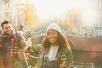 Retrato sonriente pareja joven cogida de la mano a lo largo del canal en Amsterdam - foto de stock