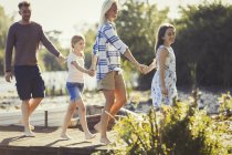 Barefoot family holding hands and walking on dock — Stock Photo