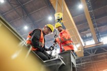Steel workers fastening steel to crane in factory — Stock Photo