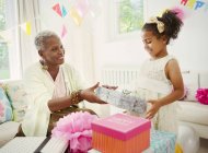 Menina dando presente de aniversário à avó na festa — Fotografia de Stock