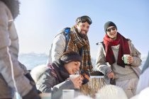 Smiling skier friends drinking coffee and hot cocoa outside apres-ski — Stock Photo