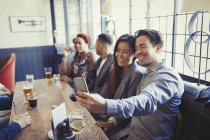 Casal sorrindo tirando selfie com telefone da câmera na mesa no bar — Fotografia de Stock