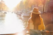 Femme regardant la vue ensoleillée sur le canal d'automne, Amsterdam — Photo de stock
