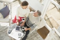 View from above mature couple drinking coffee and using digital tablet on sun porch — Stock Photo