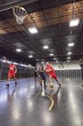 Jóvenes jugadores de baloncesto jugando baloncesto en la cancha en el gimnasio - foto de stock