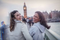 Retrato sonriente, mujeres amigas entusiastas caminando en puente hacia Big Ben, Londres, Reino Unido - foto de stock