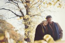 Ласковая старшая пара обнимается в солнечном осеннем парке — стоковое фото