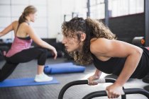 Déterminé jeune femme faisant push-ups avec de l'équipement dans la salle de gym — Photo de stock