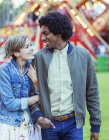 Молода багаторасова пара посміхається один одному в парку розваг — стокове фото