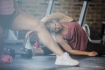 Mujer joven estirando piernas y lado en el gimnasio - foto de stock