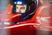 Close up focused formula one driver wearing helmet in race car — Stock Photo