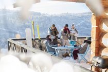 Skier and snowboarder couples hanging out on sunny cabin balcony apres-ski — Stock Photo