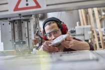 Männlicher Designer trägt Ohrenschutz, begutachtet Prototyp in der Werkstatt — Stockfoto