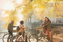 Friends with bicycles along sunny autumn canal in Amsterdam — Stock Photo