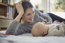 Smiling mother looking at baby daughter — Stock Photo