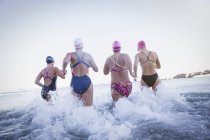 Mulheres nadadoras ativas correndo no oceano ao ar livre — Fotografia de Stock