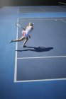 Молодая теннисистка играет в теннис, размахивая теннисной ракеткой на солнечном синем теннисном корте — стоковое фото