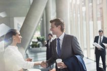 Businessman and businesswoman handshaking in sunny office lobby — Stock Photo
