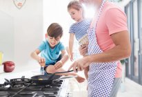 Padre cucina la colazione al fornello con figlia e figlio — Foto stock
