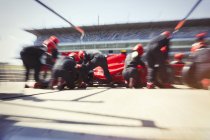 Tripulación de pozos reemplazando neumáticos en un coche de fórmula de carrera en pit lane - foto de stock