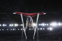 Male gymnast performing upside-down splits on parallel bars in arena — Stock Photo