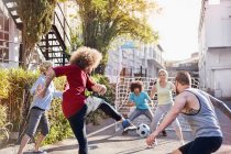 Friends playing soccer in sunny summer street — Stock Photo