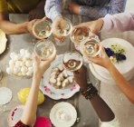 Overhead view friends toasting champagne glasses over Easter desserts — Stock Photo