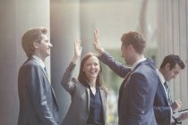 Business people high-fiving in office lobby — Stock Photo