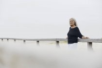Selbstbewusste Seniorin lehnt an Strandpromenade-Geländer — Stockfoto