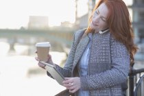 Femme d'affaires multitâche, boire du café et utiliser une table numérique tout en parlant sur un téléphone portable — Photo de stock