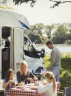 Famille profitant du petit déjeuner à table à l'extérieur camping-car ensoleillé — Photo de stock