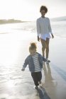 Mother and daughter walking on beach — Stock Photo