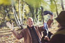 Seniorchef posiert im Herbstpark für Ehefrau mit Kameratelefon — Stockfoto